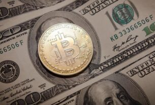 Bitcoin token is laying on a stash of dollar banknotes