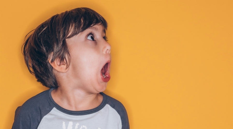 A young boy is screaming on a yellow background